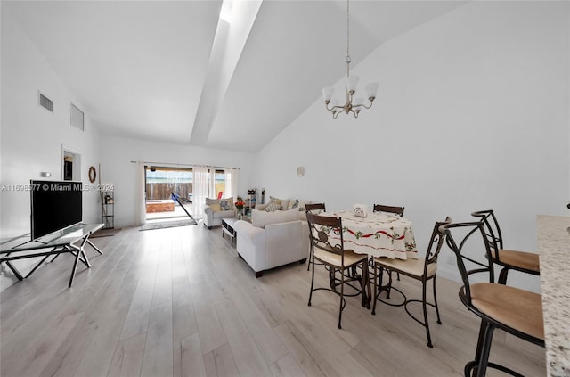 living room with a notable chandelier, high vaulted ceiling, and light hardwood / wood-style flooring