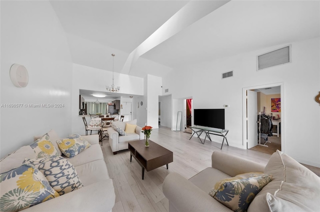 living room with light hardwood / wood-style floors, high vaulted ceiling, and a chandelier