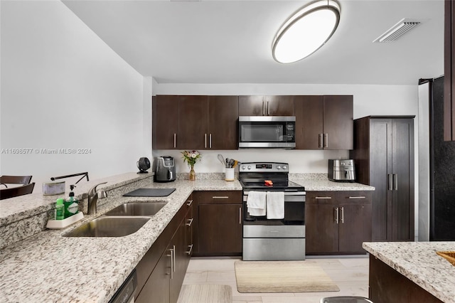 kitchen with light stone countertops, dark brown cabinetry, stainless steel appliances, and sink