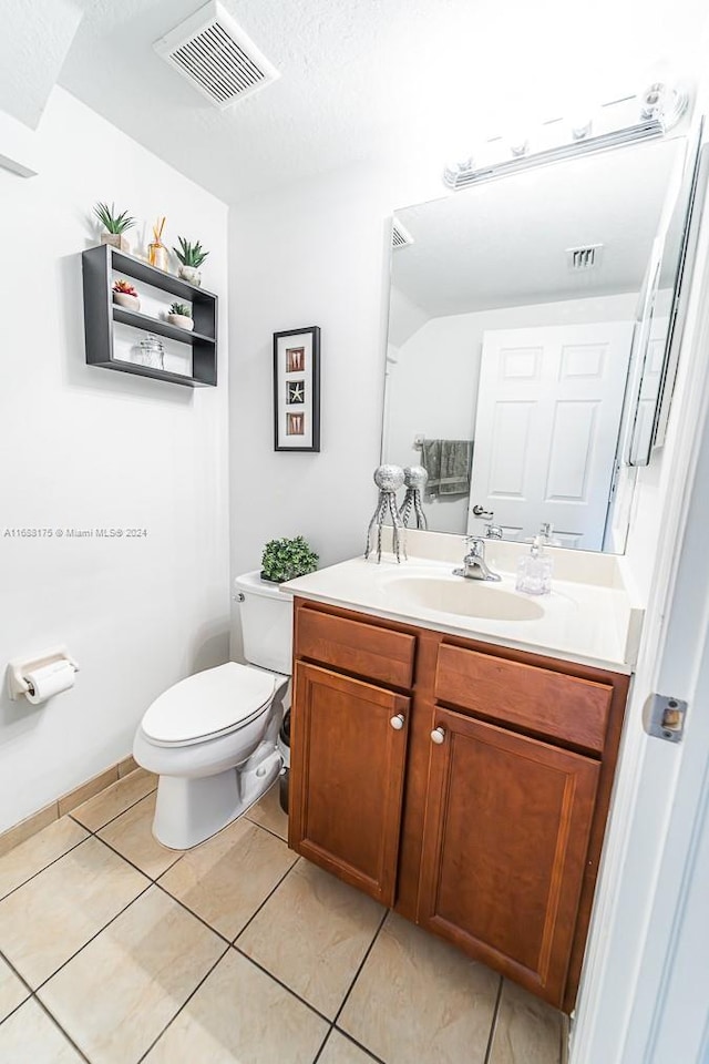 bathroom with tile patterned floors, vanity, a textured ceiling, and toilet