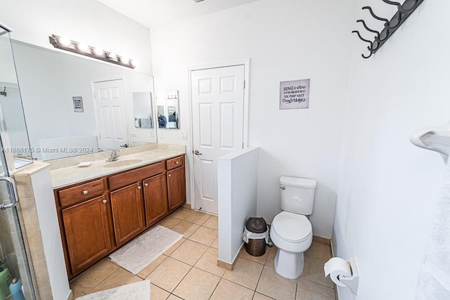 bathroom with tile patterned flooring, vanity, a shower with shower door, and toilet