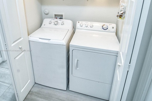 clothes washing area with separate washer and dryer and light hardwood / wood-style floors