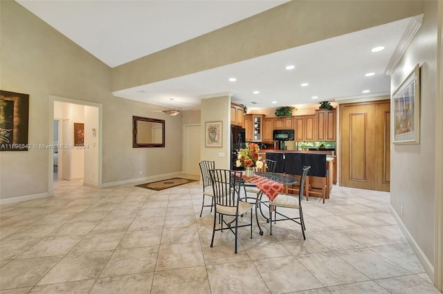 dining room featuring light tile patterned flooring, vaulted ceiling, and ornamental molding