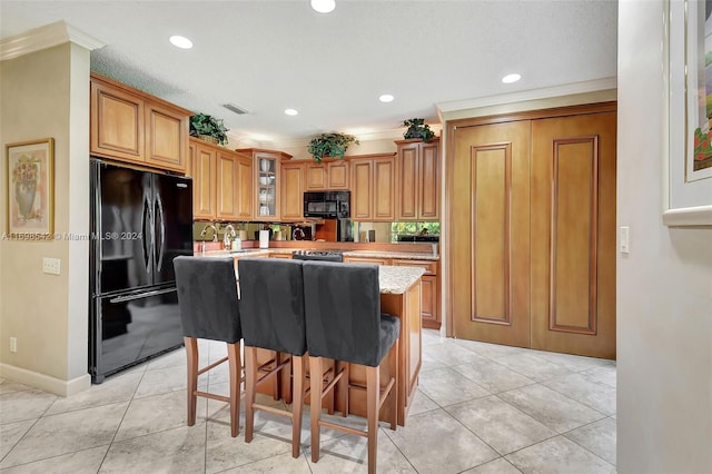 kitchen with a kitchen breakfast bar, crown molding, light tile patterned flooring, and black appliances