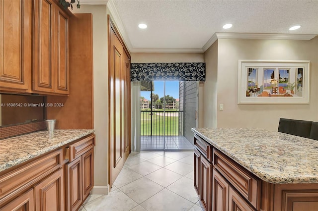 kitchen featuring a textured ceiling, light stone countertops, and crown molding