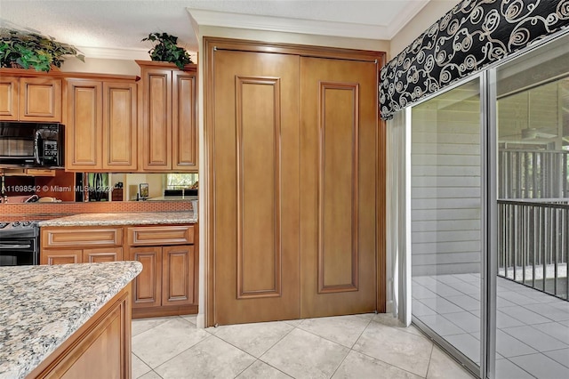 kitchen featuring light stone countertops, a textured ceiling, light tile patterned flooring, black appliances, and ornamental molding