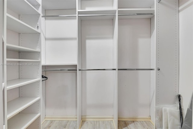 walk in closet with light hardwood / wood-style flooring