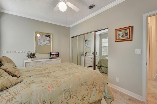 bedroom with ceiling fan, light hardwood / wood-style flooring, crown molding, a textured ceiling, and a closet