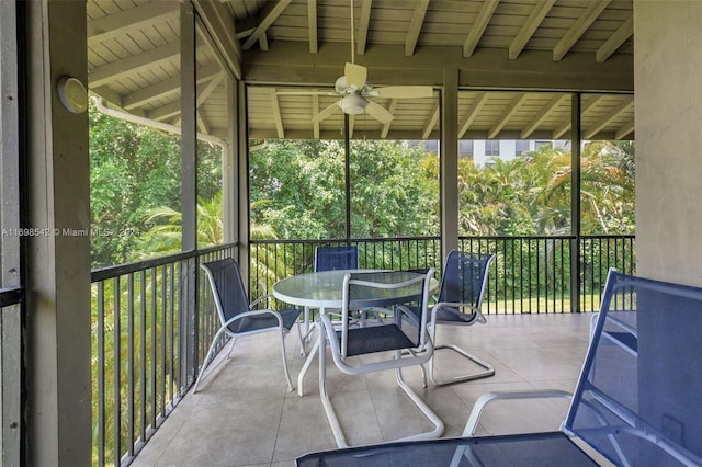 unfurnished sunroom with vaulted ceiling with beams, a wealth of natural light, and ceiling fan