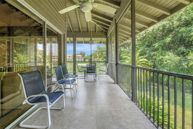 unfurnished sunroom featuring vaulted ceiling with beams and ceiling fan