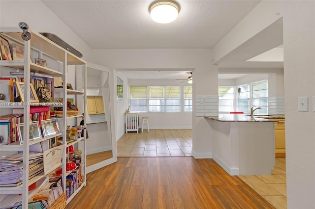 interior space featuring decorative backsplash, light hardwood / wood-style floors, a textured ceiling, and ceiling fan