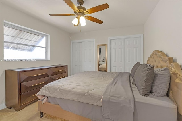 carpeted bedroom with multiple closets and ceiling fan