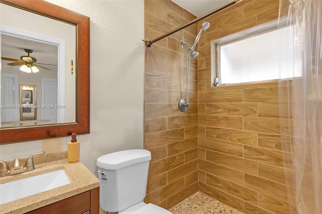 bathroom featuring tiled shower, vanity, toilet, and ceiling fan