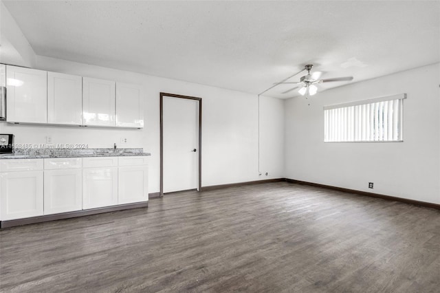 unfurnished living room with a textured ceiling, dark hardwood / wood-style floors, and ceiling fan