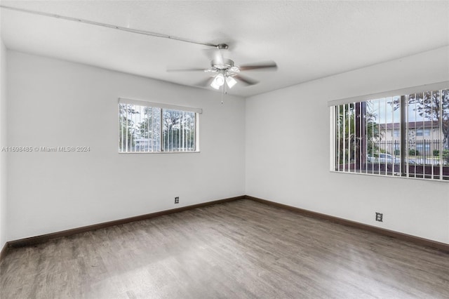 unfurnished room featuring ceiling fan, wood-type flooring, and a wealth of natural light