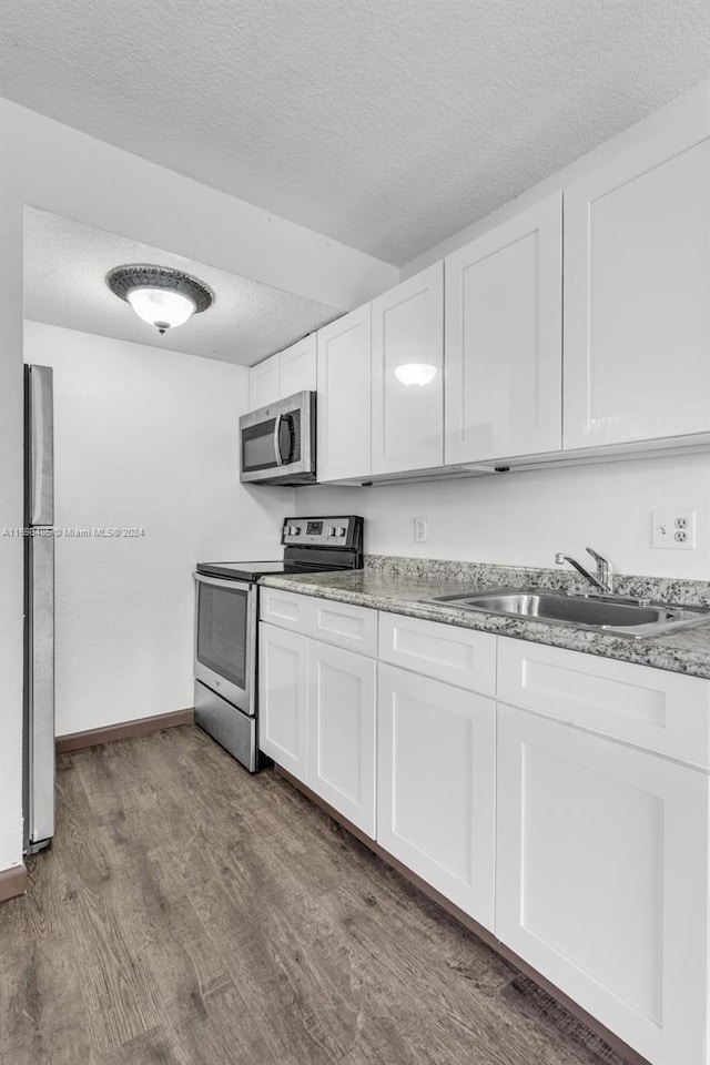 kitchen with dark hardwood / wood-style floors, sink, white cabinetry, and stainless steel appliances