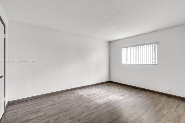 unfurnished room featuring hardwood / wood-style floors and a textured ceiling