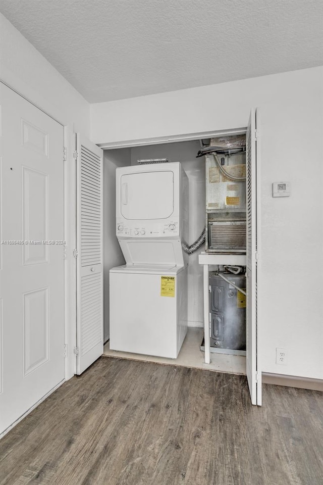 washroom with a textured ceiling, stacked washer and dryer, and hardwood / wood-style flooring