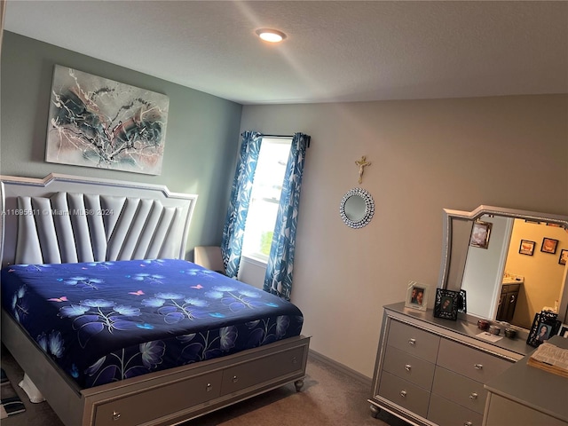 bedroom featuring ensuite bath and dark colored carpet