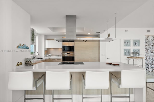 kitchen featuring black appliances, a kitchen breakfast bar, kitchen peninsula, and sink