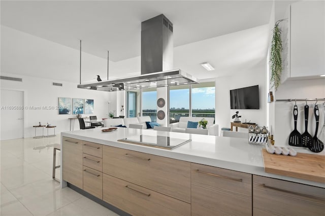 kitchen with island range hood, black electric stovetop, and light tile patterned flooring