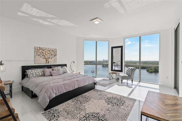 bedroom with a water view, a wall of windows, access to outside, and light tile patterned floors