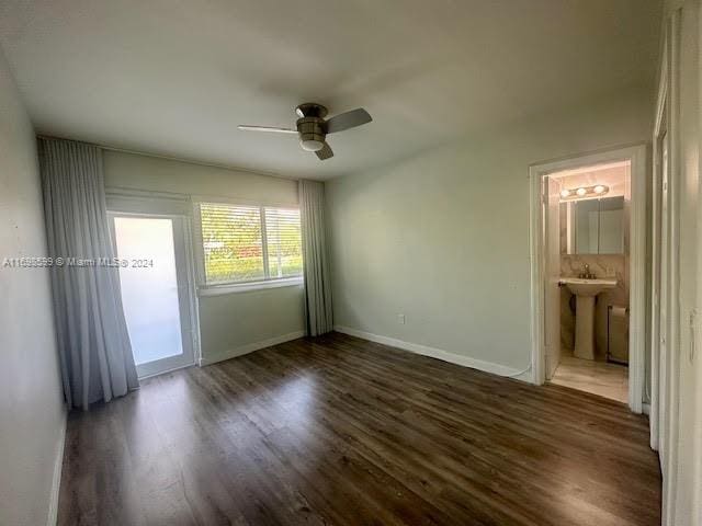 unfurnished bedroom featuring ensuite bathroom, dark hardwood / wood-style flooring, and ceiling fan