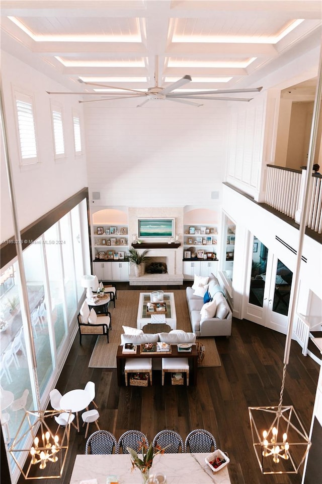 living room featuring coffered ceiling, dark hardwood / wood-style flooring, beamed ceiling, and ceiling fan with notable chandelier