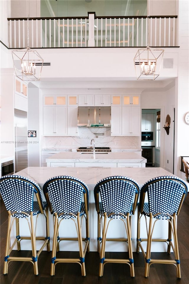 kitchen with tasteful backsplash, white cabinetry, dark wood-type flooring, and decorative light fixtures