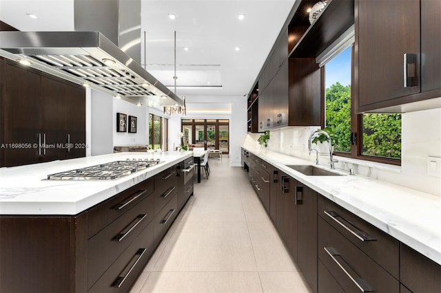 kitchen with sink, pendant lighting, light tile patterned floors, stainless steel gas stovetop, and range hood