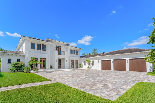 view of front facade featuring a garage, a balcony, and a front lawn