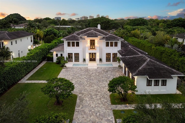 back house at dusk featuring a patio and a balcony