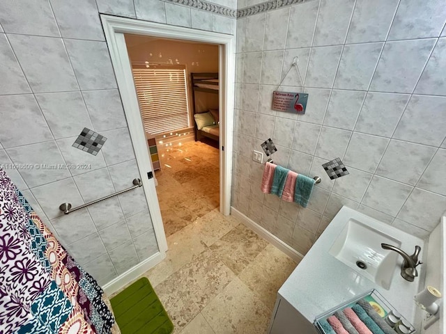 bathroom with a shower, sink, and tile walls