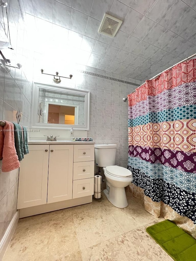 bathroom with a shower with curtain, vanity, toilet, and tile walls