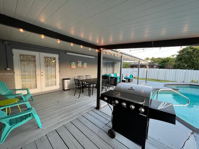 deck with french doors, a fenced in pool, and grilling area