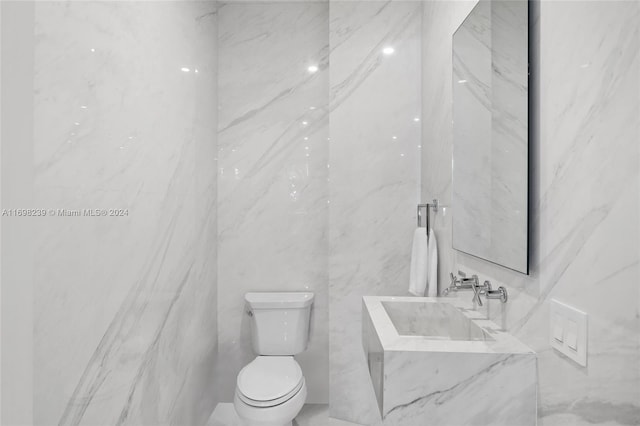 bathroom with sink, toilet, and tile walls