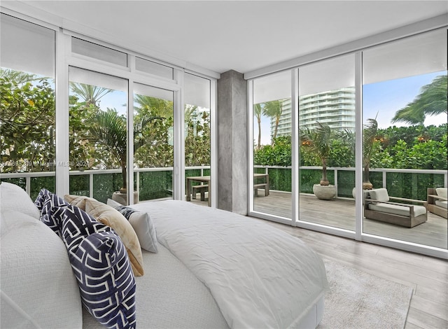 bedroom with hardwood / wood-style floors, access to outside, and a wall of windows