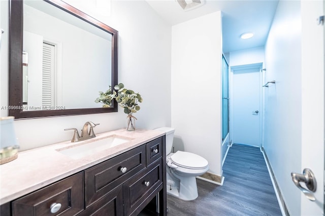 bathroom featuring wood-type flooring, vanity, toilet, and a shower with door