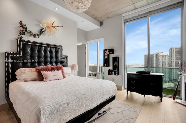 bedroom with hardwood / wood-style floors and a water view