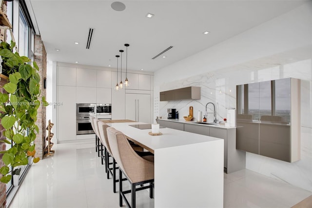 kitchen with decorative light fixtures, a kitchen island, tasteful backsplash, and sink