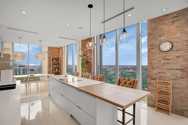 kitchen featuring a breakfast bar, light tile patterned floors, white cabinetry, and a wall of windows