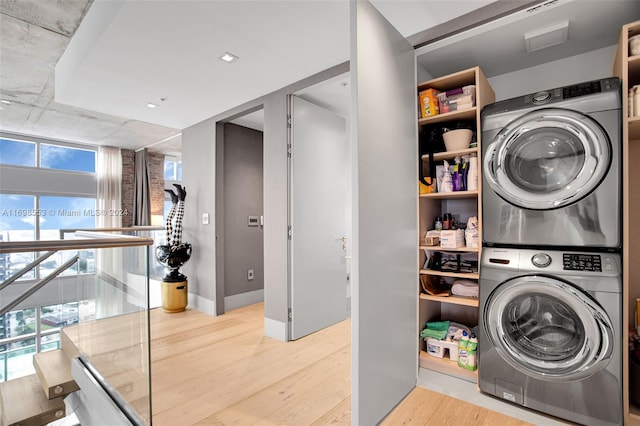 clothes washing area featuring light hardwood / wood-style floors and stacked washer and dryer