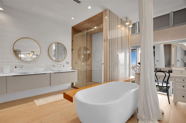 bathroom featuring vanity, plus walk in shower, wood-type flooring, and tile walls