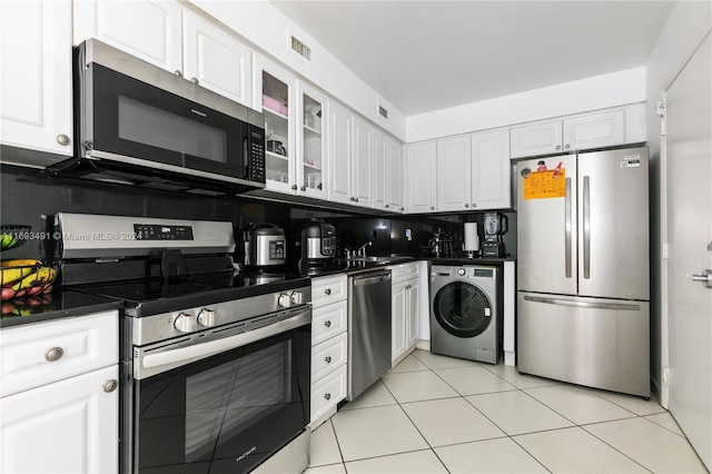 kitchen featuring washer / clothes dryer, white cabinetry, light tile patterned floors, and appliances with stainless steel finishes