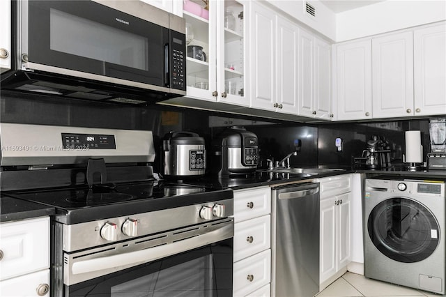 kitchen with white cabinetry, sink, stainless steel appliances, washer / dryer, and decorative backsplash