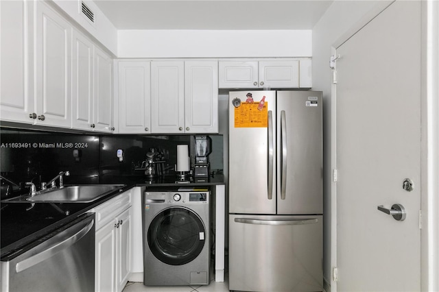 kitchen featuring backsplash, stainless steel appliances, sink, washer / clothes dryer, and white cabinetry