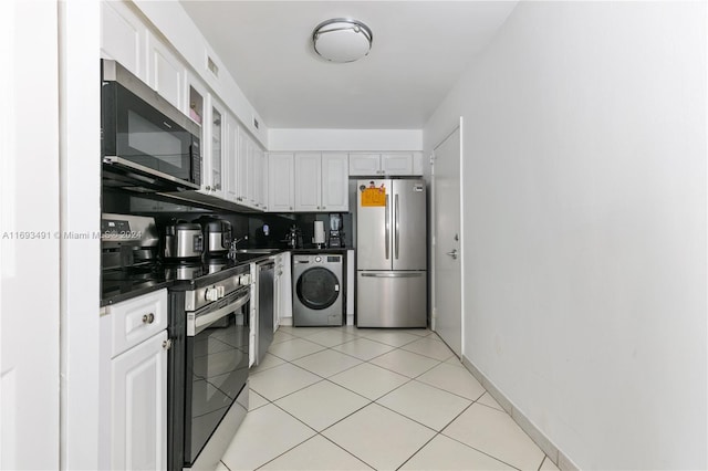 kitchen with stainless steel appliances, sink, light tile patterned floors, washer / dryer, and white cabinetry