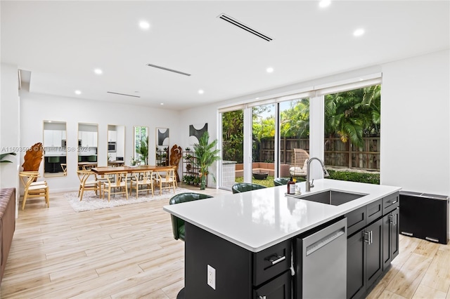 kitchen with a center island with sink, stainless steel dishwasher, light wood-type flooring, and sink