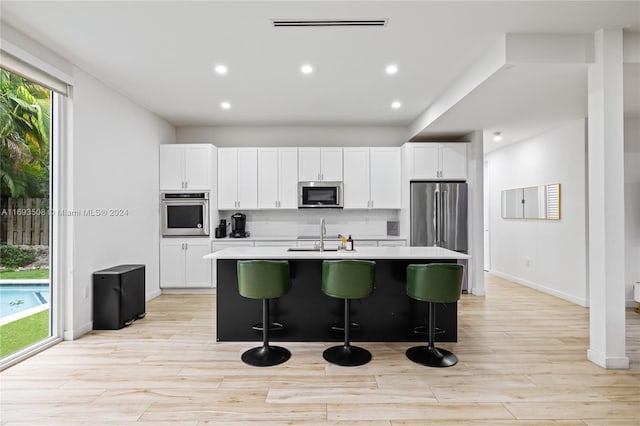 kitchen featuring a kitchen bar, a wealth of natural light, an island with sink, and stainless steel appliances