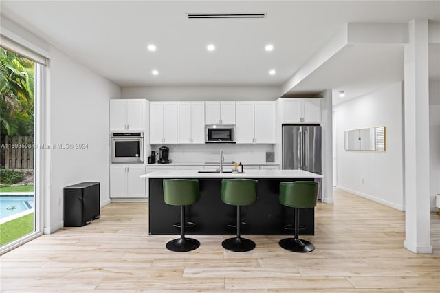 1816 SW 23rd St, Miami, FL 33145 - kitchen featuring appliances with stainless steel finishes, an island with sink, white cabinets, light wood finished floors, and recessed lighting